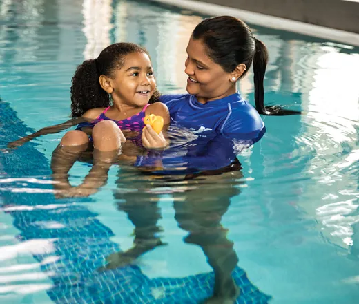 swim instructor teaching young girl in pool