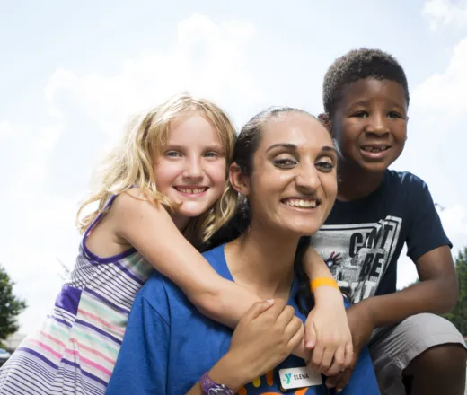 two children hugging their camp counselor